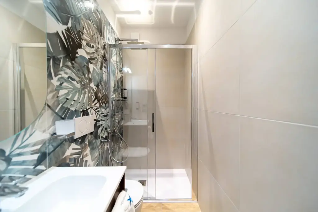 Bagno moderno con doccia e carta da parati tropicale.