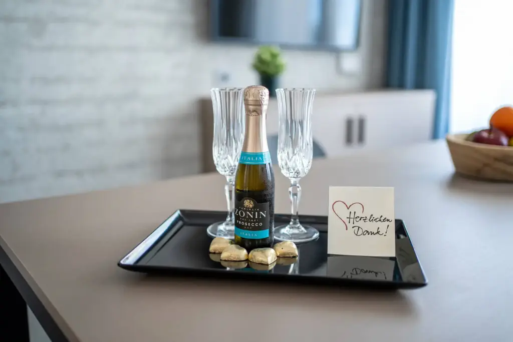 Bottiglia di prosecco con calici su vassoio nero.