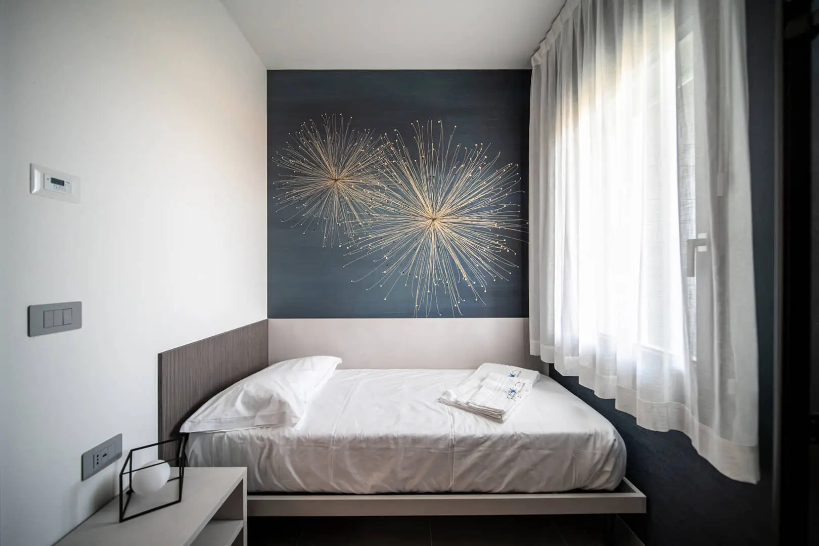 Letto singolo in camera con decorazione murale.