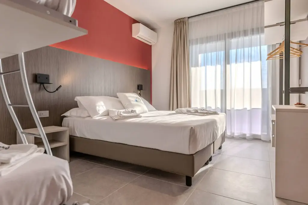 Camera moderna con letto matrimoniale e grandi finestre.