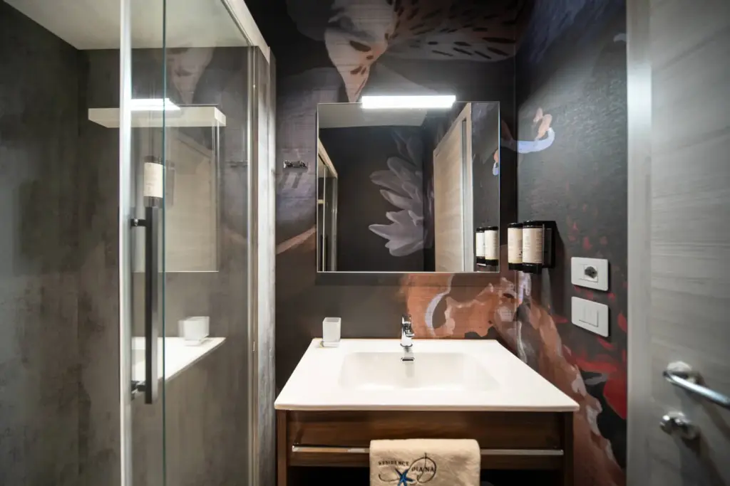 Bagno moderno con doccia e lavabo, motivo floreale.