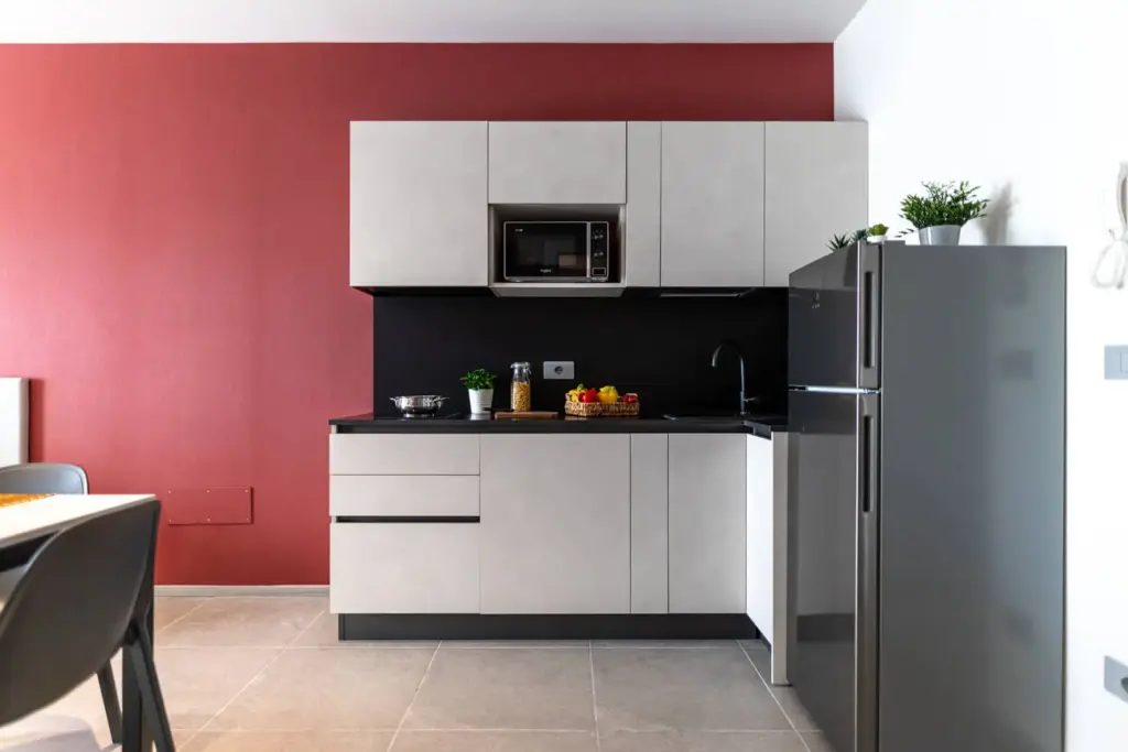 Cucina moderna con parete rossa e mobili grigi.