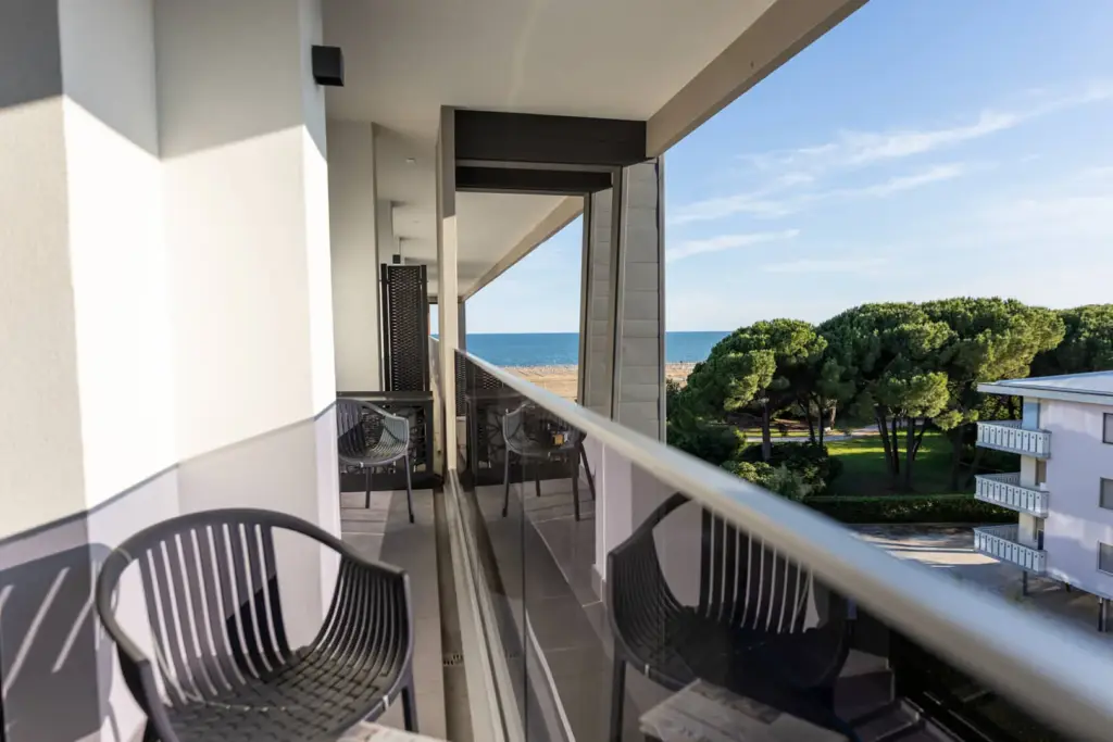 Balcone moderno con vista mare e alberi verdi.
